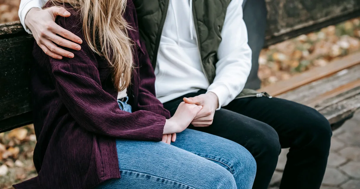 Casal abraçado sentado em um banco de jardim, visita íntima em clínica de reabilitação