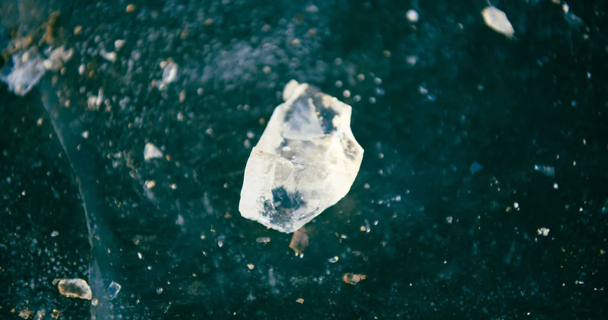 Fragmento de cristal translúcido sobre fundo escuro em macro, o que é metanfetamina cristal