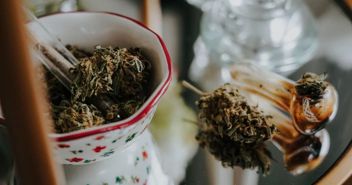 Flores de cannabis secas em um pote e sobre a mesa, o skank produzido a partir de flores selecionadas